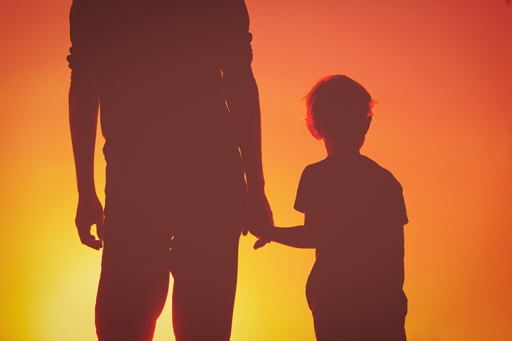 silhouette of father and son holding hands at sunset sky