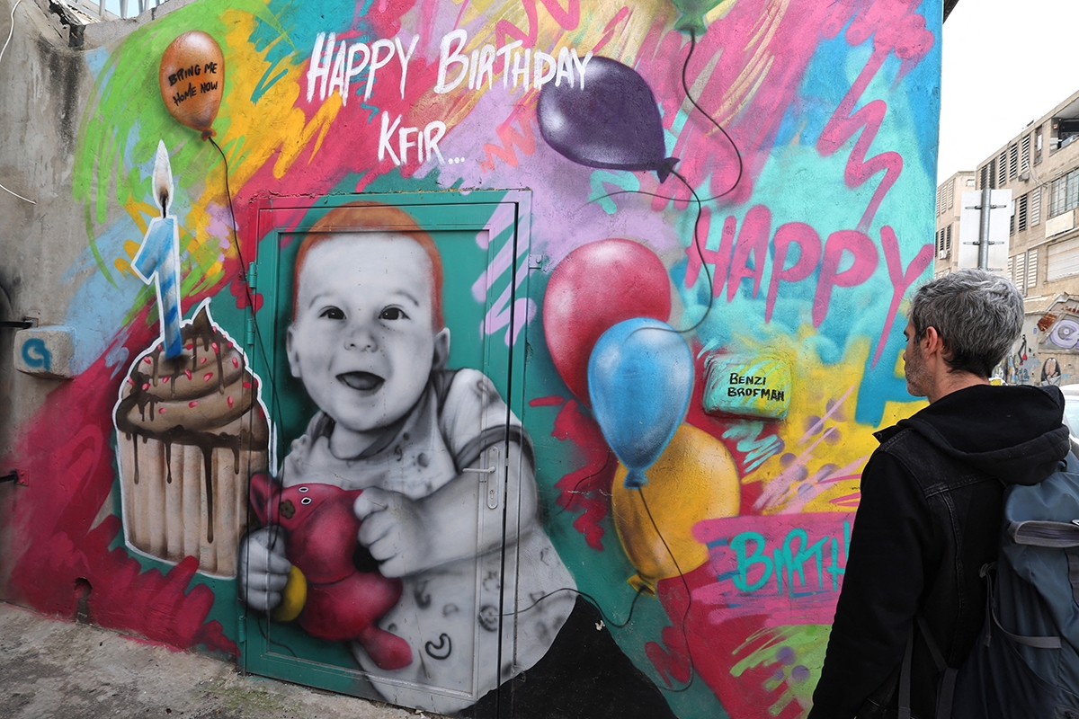 A man walks past a mural paiting representing a baby from the Bibas family, held by Hamas in Gaza since October 7, 2023, on a wall in the Israeli coastal city of Tel Aviv on February 19, 2025